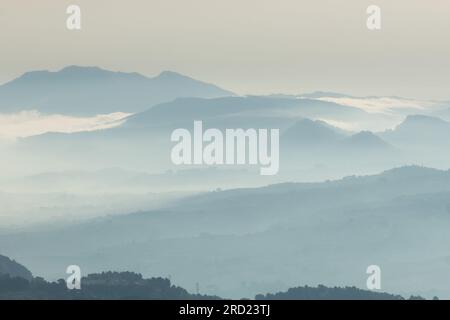 Silhouettes de montagnes stratifiées englouties dans une couverture de brume de l'Alt de les Pedreres à Alcoy, Espagne Banque D'Images