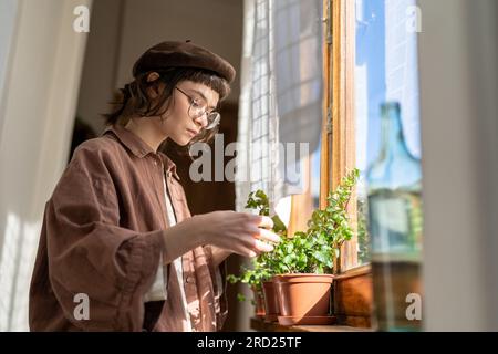 Hipster fille prenant soin de plantes de maison, vérifier si la plante est saine. Amoureux des plantes. Banque D'Images