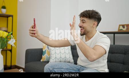 Jeune arabe ayant un appel vidéo assis sur un canapé à la maison Banque D'Images