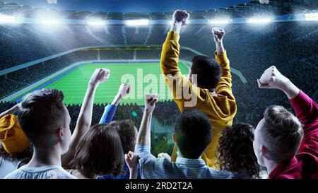 Les supporters de Backview dans les tribunes soutiennent leur équipe favorite au championnat en soirée. Concept de sport, émotions, jeux, victoire et succès. Banque D'Images