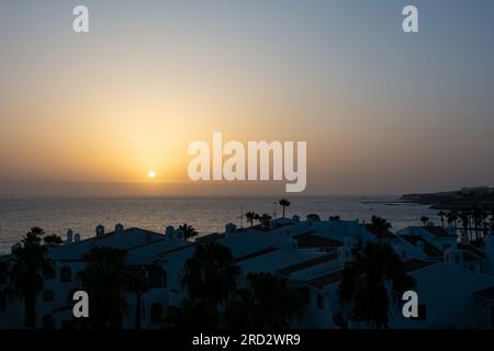 Coucher de soleil sur la mer avec complexe de bungalows en premier plan dans la ville canari de Costa Adeje, Tenerife, Espagne Banque D'Images