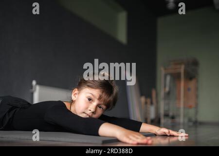 Jeune fille de 4 ans faisant des exercices d'étirement pendant son cours de sport d'entraînement de danse ou de gymnastique. L'éducation active des enfants par l'athlète Banque D'Images