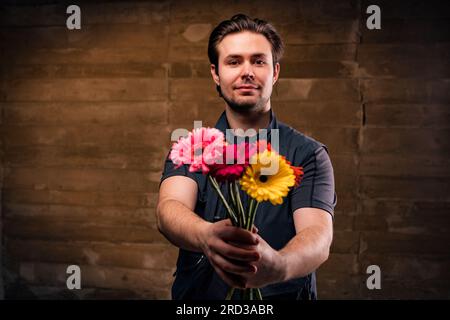 Young handsome positive man giving bouquet of flowers Banque D'Images