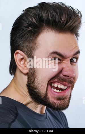 Jeune fou danger homme portrait émotionnel sur fond blanc Banque D'Images