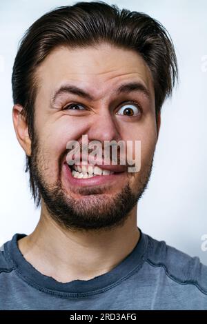 Jeune fou danger homme portrait émotionnel sur fond blanc Banque D'Images