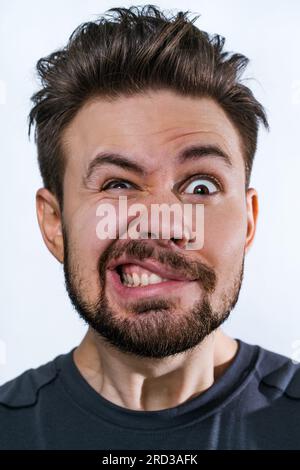 Jeune fou danger homme portrait émotionnel sur fond blanc Banque D'Images