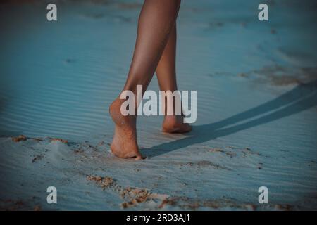 Jeune femme marche pieds nus sur le sable le soir Banque D'Images