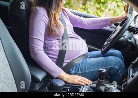 Une femme enceinte portant une ceinture de sécurité conduit une