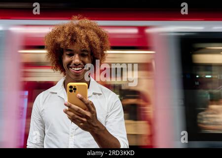 young african american man standing in Subway using smartphone Banque D'Images