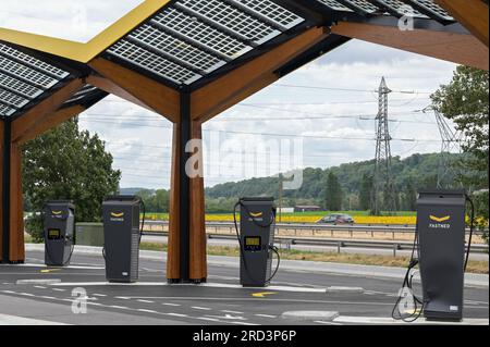 FRANCE, Fastned station de recharge rapide pour véhicule électrique à la station-service sur autoroute, cellules solaires sur toit / FRANKREICH, Fastned Stromladestation für Elektrofahrzeuge an Dyneff Tankstelle an der Autobahn, Solarzellen auf Dach, Hintergrund Sonnenblume Feld Banque D'Images