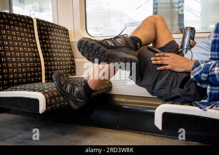 Un passager en tube est assis avec un coffre reposant sur le siège en tissu d'un train voyageant sur la Metropolitan Line dans le centre de Londres , le 18 juillet 2023, à Londres, Angleterre. Banque D'Images