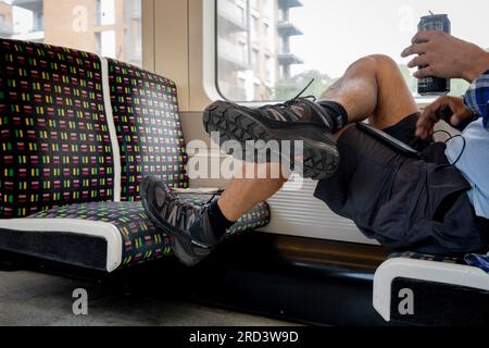 Un passager en tube est assis avec un coffre reposant sur le siège en tissu d'un train voyageant sur la Metropolitan Line dans le centre de Londres , le 18 juillet 2023, à Londres, Angleterre. Banque D'Images