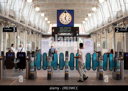 Deux jours avant l'élection partielle politique, les voyageurs en métro franchissent les barrières à la station de métro Uxbridge qui est desservie par les lignes Metropolitan et Piccadilly, le 18 juillet 2023, à Londres, Angleterre. La circonscription d'Uxbridge et de South Ruislip est l'une des trois élections partielles locales tenues le même jour, mais Uxbridge a été représentée au Parlement par l'ancien Premier ministre conservateur Boris Johnson pendant huit ans avant de démissionner de son poste de député. Il sera contesté par 17 candidats le 20 juillet. Banque D'Images