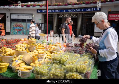 Deux jours avant l'élection partielle politique, les résidents achètent des fruits et légumes devant la station de métro Uxbridge, le 18 juillet 2023, à Londres, en Angleterre. La circonscription d'Uxbridge et de South Ruislip est l'une des trois élections partielles locales tenues le même jour, mais Uxbridge a été représentée au Parlement par l'ancien Premier ministre conservateur Boris Johnson pendant huit ans avant de démissionner de son poste de député. Il sera contesté par 17 candidats le 20 juillet. Banque D'Images