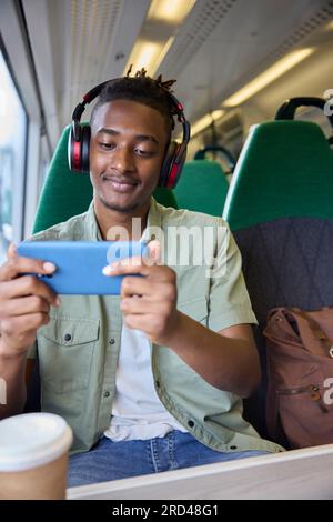 Young Man se rend au travail assis sur le train Streaming et regarder un film ou une émission sur téléphone portable Banque D'Images