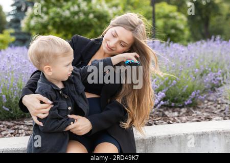 Mère enceinte et son petit fils passant du temps ensemble dans le parc, étreignant et souriant. Banque D'Images