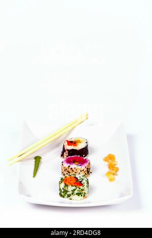 Rouleaux de sushi vegan et une paire de baguettes sur une assiette blanche avec espace de copie Banque D'Images