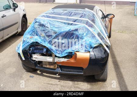 Schuttern, Allemagne, 29 avril 2023 : une voiture endommagée par un accident est enveloppée dans un film dans un parking. Portes arrière et pare-chocs cassés visibles. Banque D'Images