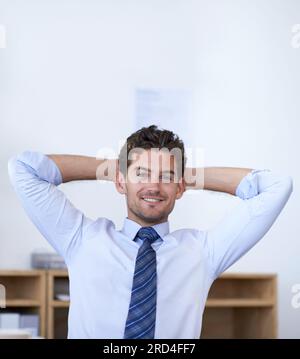 Travail fait, pas de stress. Photo recadrée d'un beau jeune homme d'affaires à l'air détendu au bureau. Banque D'Images