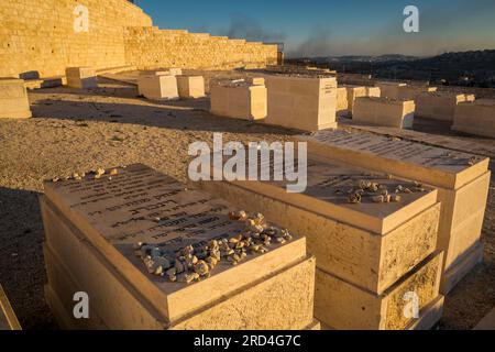 Vue rapprochée horizontale de certaines des tombes du cimetière juif du mont des oliviers avec la fumée sur la bande de Gaza en arrière-plan, Jérusalem Banque D'Images