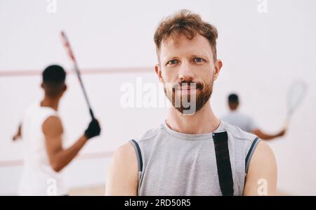 Apportez votre meilleur et les malades apportent le mien. Portrait d'un jeune homme jouant à une partie de squash avec ses coéquipiers en arrière-plan. Banque D'Images