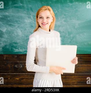 Portrait de femme enseignante dans la salle de classe tableau avant. Professeur souriant avec cahier. Journée des enseignants. Heureux étudiant ou enseignant dans la salle de classe près Banque D'Images