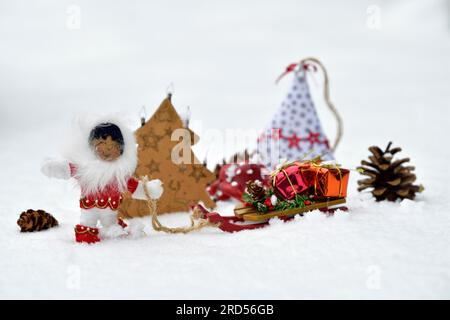 Décoration de Noël, Inuit tirant le traîneau avec des cadeaux de Noël à travers la neige Banque D'Images