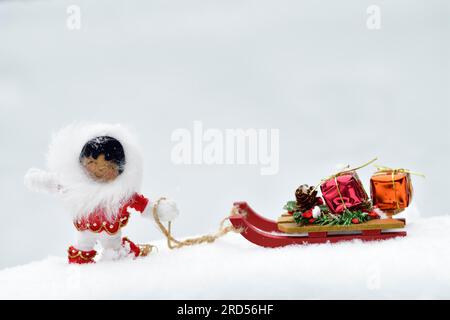 Décoration de Noël, Inuit tirant le traîneau avec des cadeaux de Noël à travers la neige Banque D'Images