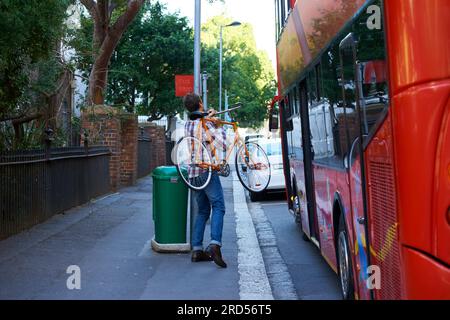 En route pour le travail. Plan d'un homme avec son vélo à un arrêt de bus. Banque D'Images
