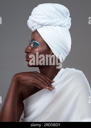 Les accessoires les plus simples parlent le plus fort. Photo en studio d'une jeune femme séduisante posant en tenue africaine traditionnelle sur fond gris. Banque D'Images