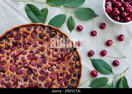 Délicieux clafoutis de cerise dans un plat de cuisson rond sur fond clair. Tarte aux baies maison fraîche. Dessert traditionnel français. mise au point sélective Banque D'Images