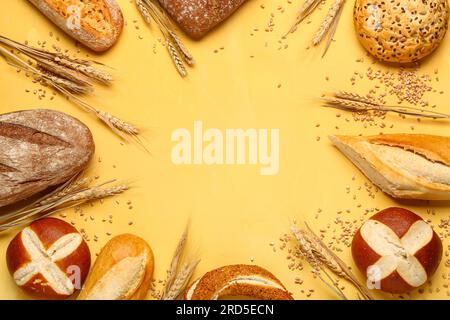 Cadre fait de différents types de pain et épis de blé sur fond jaune Banque D'Images