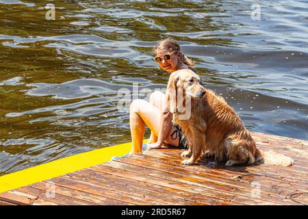 Femme et son chien de compagnie assis sur un flotteur de natation dans le lac Sparrow Muskoka Ontario Canada Banque D'Images