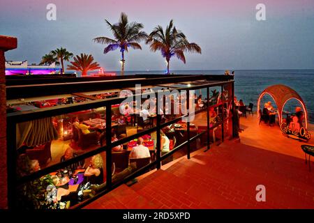 Lanzarote Îles Canaries Puerto Del Carmen le restaurant Cafe la Ola sur la rue principale donnant sur la plage et les palmiers avec bleu clair t Banque D'Images