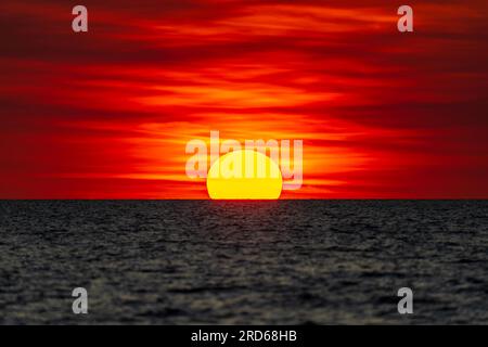 Coucher de soleil spectaculaire à l'horizon à Mindil Beach, ressemblant quelque peu au drapeau aborigène australien. Darwin, Australie. Banque D'Images
