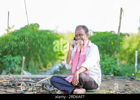 heureux fermier assis dans le sol parlant au téléphone, vieux fermier indien Banque D'Images
