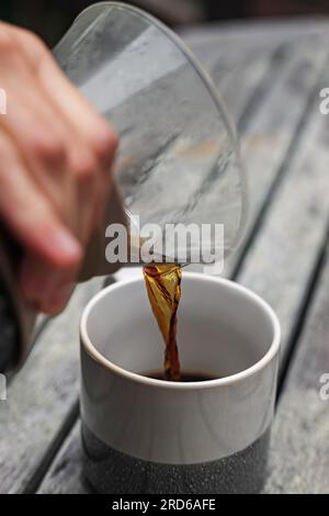 Gros plan de la main masculine qui porte du café dans la tasse Banque D'Images