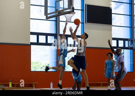 Divers joueurs de basket-ball masculins portant des vêtements de sport bleus et jouant au basket-ball à la salle de gym Banque D'Images