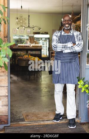 Heureux assistant de magasin afro-américain senior portant un tablier à l'épicerie biologique d'aliments naturels Banque D'Images