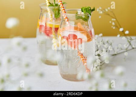 Cocktails rafraîchissants esthétiques avec agrumes et fraises en gros plan. Eau détox vitaminée d'été. Boissons à faible teneur en alcool sans résistance décorées de gypsophila. Banque D'Images