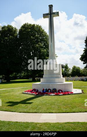 Croix commémorative avec couronnes de coquelicots au soleil au cimetière de guerre de Bayeux. Bayeux, France. Banque D'Images