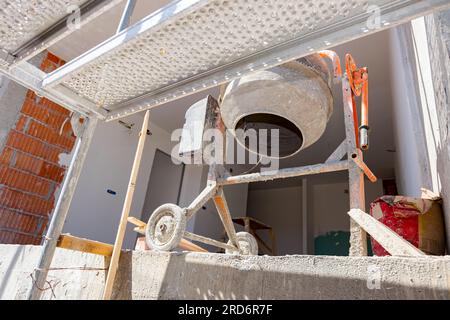 Tiré du soufflet sur la machine de mixage de ciment placée sur le balcon du bâtiment en construction, l'échafaudage est monté à côté. Banque D'Images