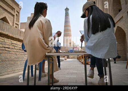 Deux filles peignent un minaret sur une toile dans les rues de Khiva, Ouzbékistan Banque D'Images