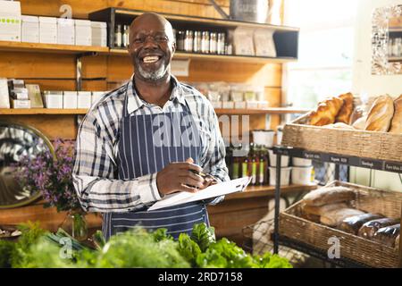 Heureux assistant de magasin afro-américain senior portant un tablier à l'épicerie biologique d'aliments naturels Banque D'Images