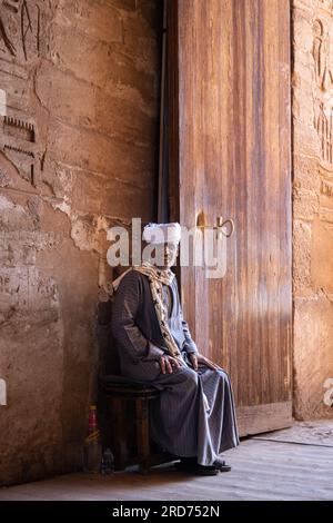 Un homme est assis près de la porte d'entrée du temple à Abu Simbel en Egypte. Banque D'Images