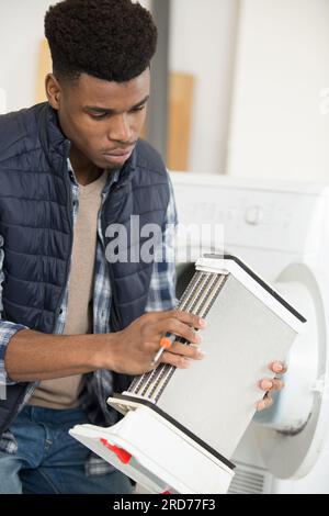 réparateur tenant le condenseur d'un sèche-linge Banque D'Images