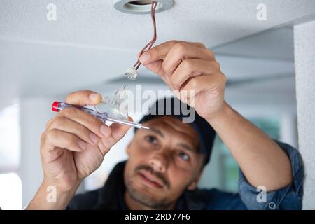 Portrait of a male electrician fixing lumière au plafond Banque D'Images