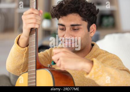 jeune homme réparateur de guitare Banque D'Images
