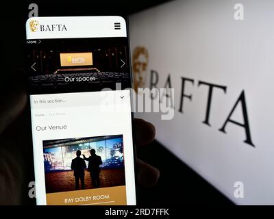 Personne tenant son smartphone avec la page Web des British Academy film Awards (BAFTA) à l'écran devant le logo. Concentrez-vous sur le centre de l'écran du téléphone. Banque D'Images