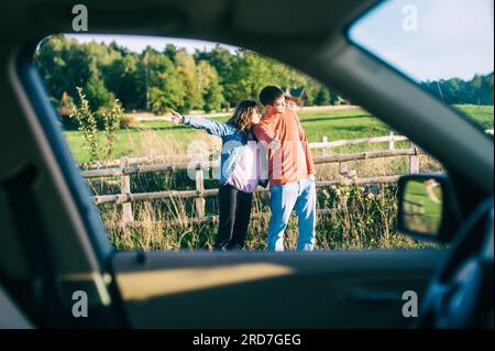 La voiture des jeunes couples est tombée en panne sur le chemin. Ils font de l'auto-stop pour trouver de l'aide. Le capot est ouvert et le moteur de la voiture est cassé Banque D'Images